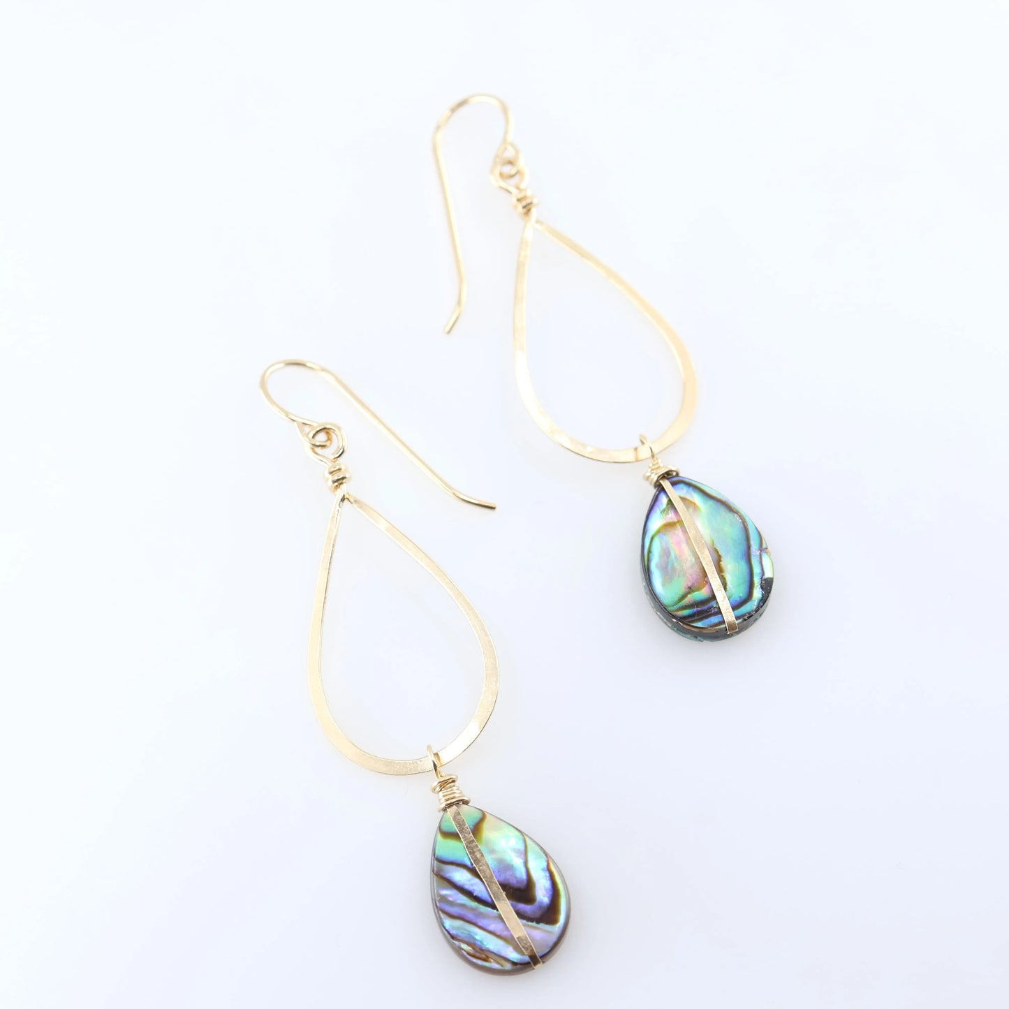 A pair of gold teardrop dangle earrings with iridescent abalone shell drops, displayed on a clean white background.