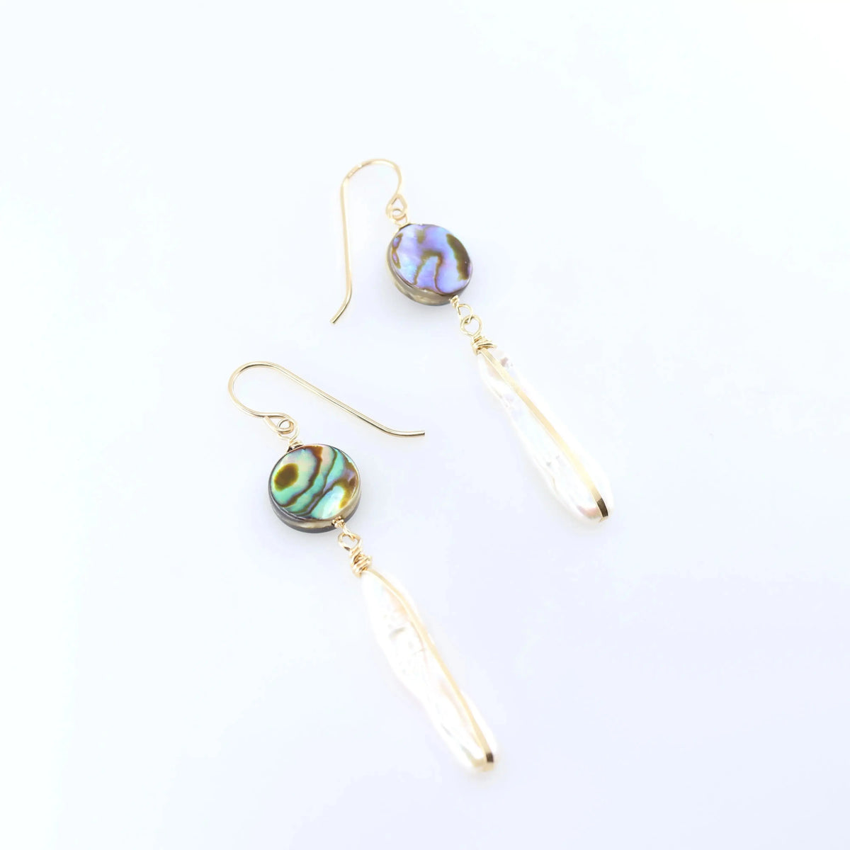 A pair of dangle earrings featuring round, iridescent green and blue Abalone and Biwa Pearl drops, shown on a clean white background.