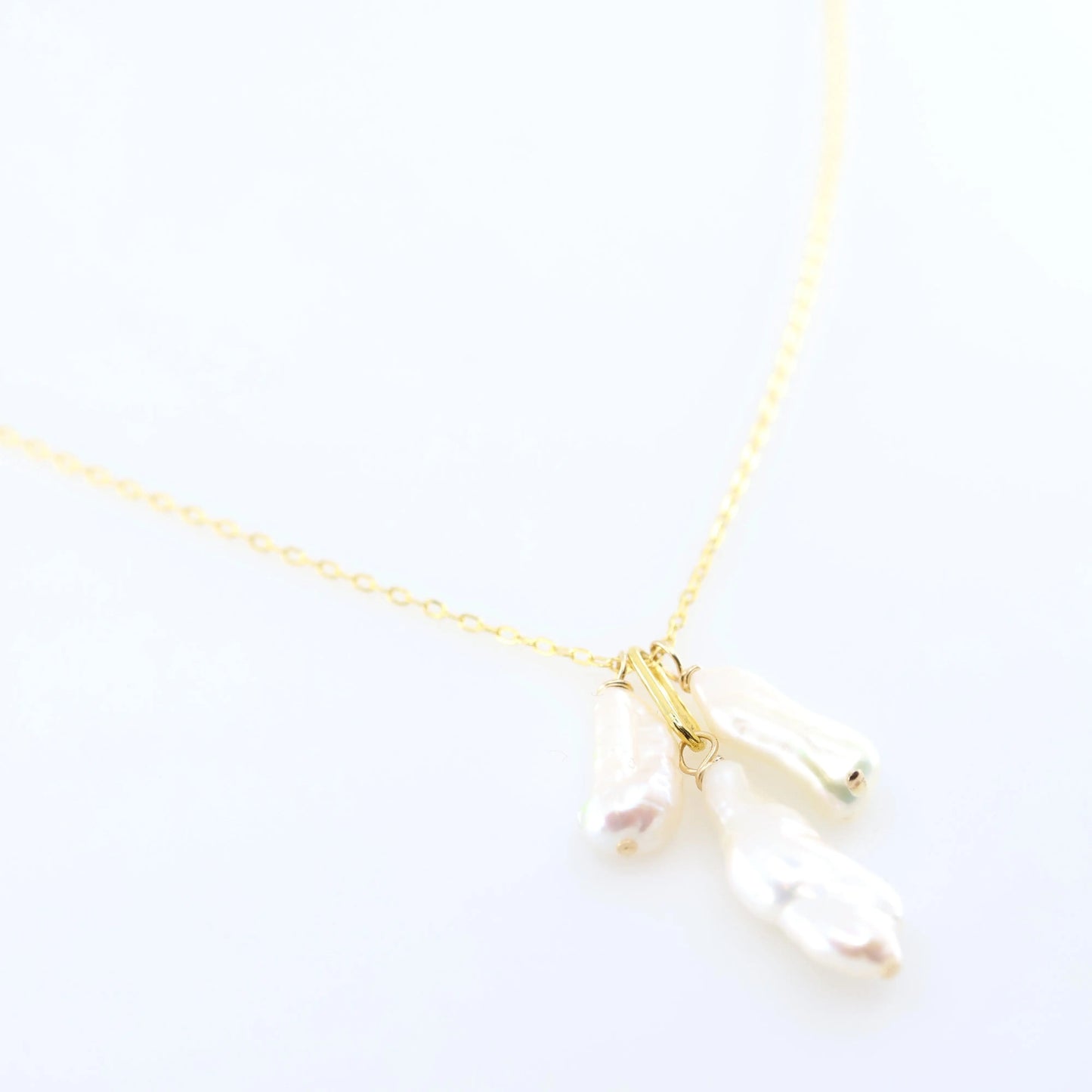 A delicate gold chain necklace featuring three small dangling Biwa Pearl charms, displayed on a clean white background.