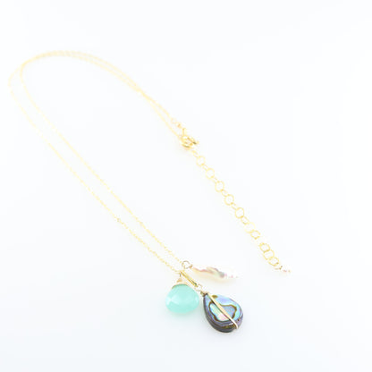 A gold chain necklace featuring triple pendant design: a faceted Dark Aqua Chalcedony gemstone, a teardrop-shaped iridescent abalone shell, and a small Biwa pearl, set against a clean white background.