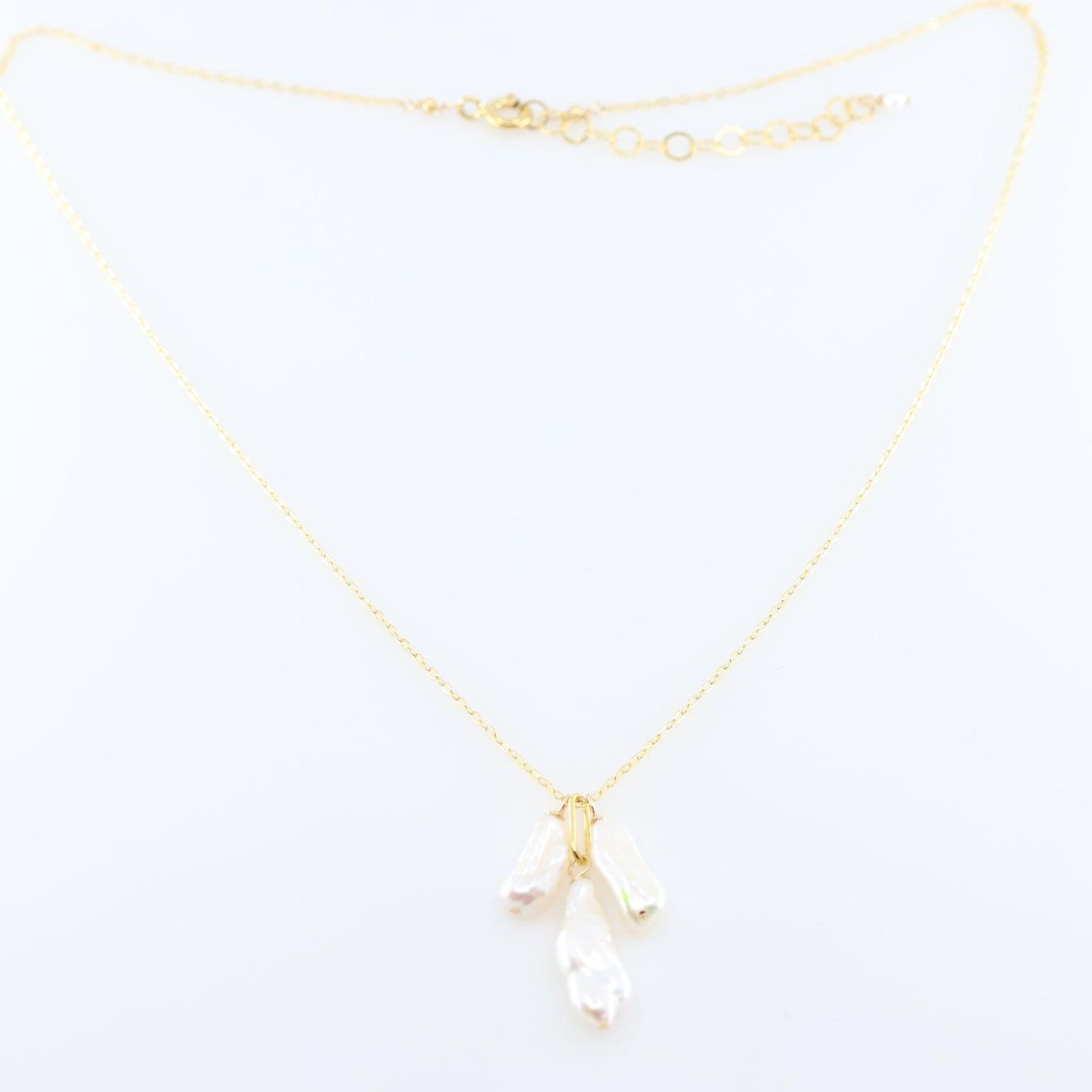 A delicate gold chain necklace featuring three small dangling Biwa Pearl charms, displayed on a clean white background.