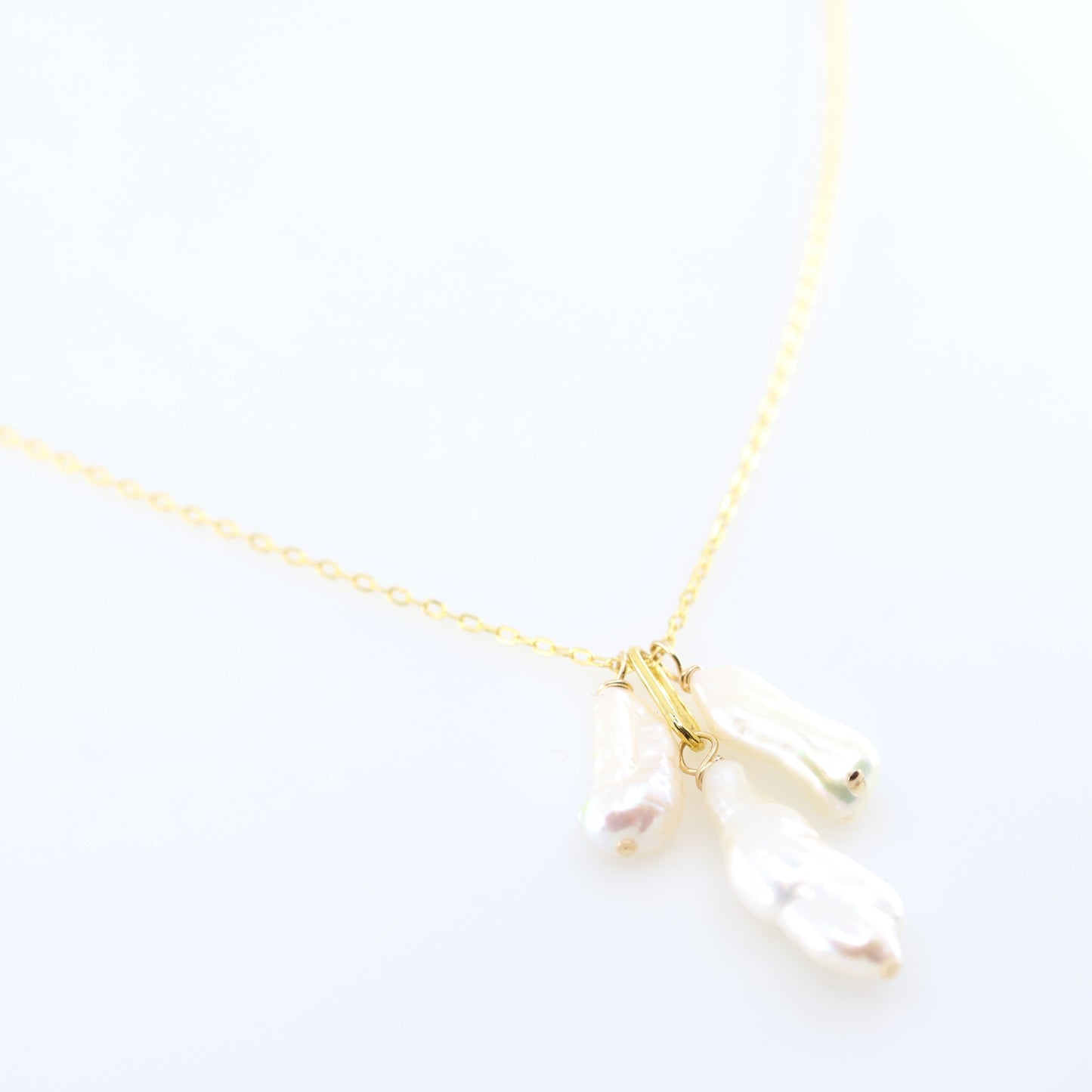 A delicate gold chain necklace featuring three small dangling Biwa Pearl charms, displayed on a clean white background.