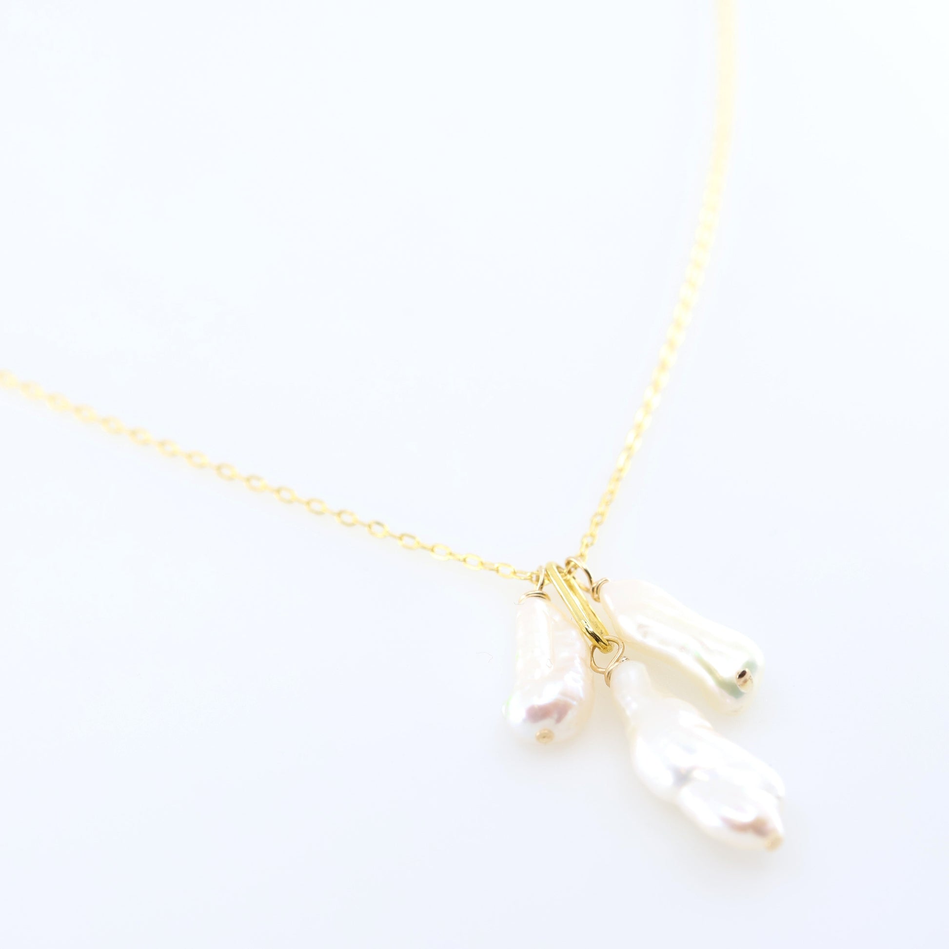 A delicate gold chain necklace featuring three small dangling Biwa Pearl charms, displayed on a clean white background.