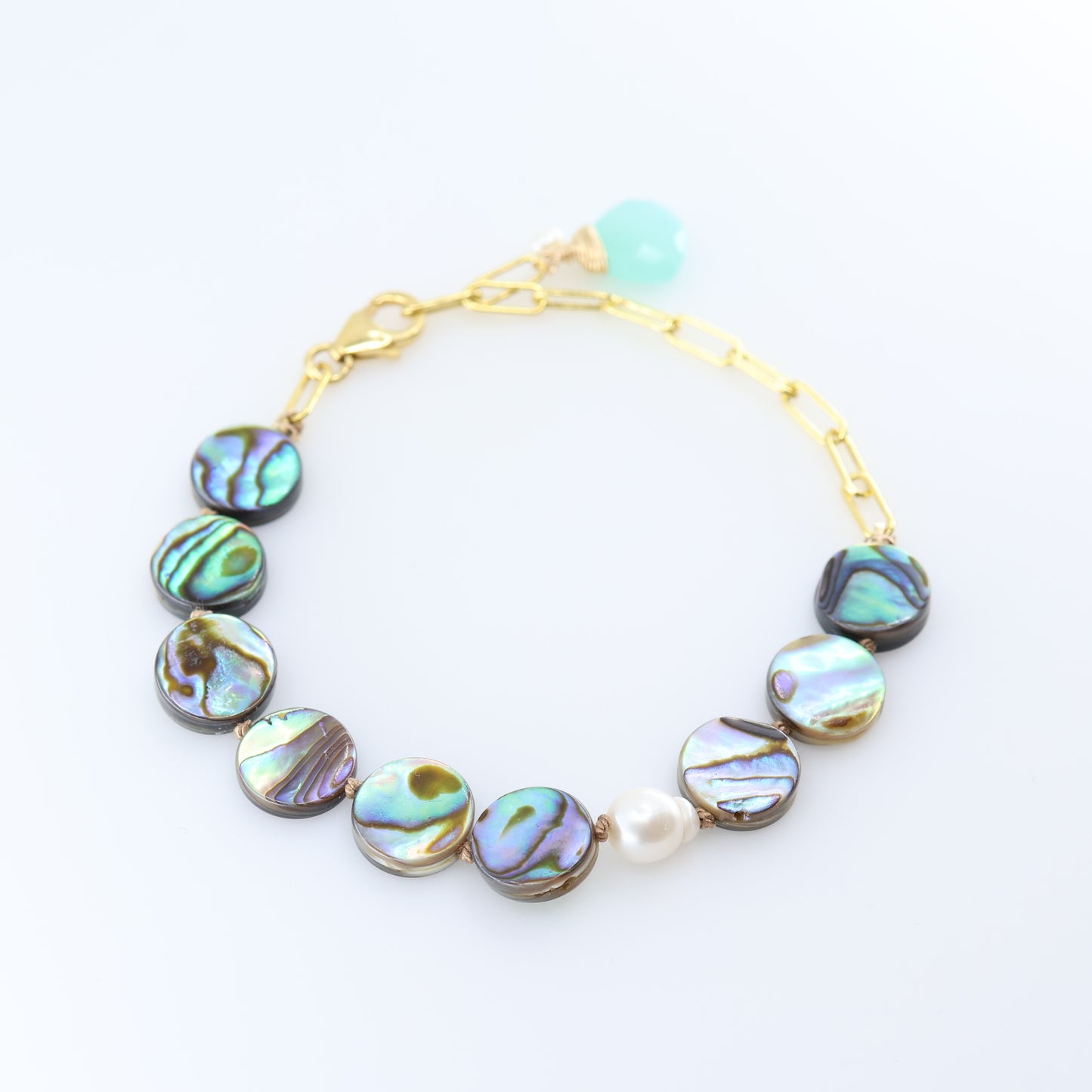 A gold chain bracelet featuring round iridescent abalone shell with shimmering green, blue, and purple hues, accented by a single white pearl bead and a Dark Aqua Chalcedony accent.