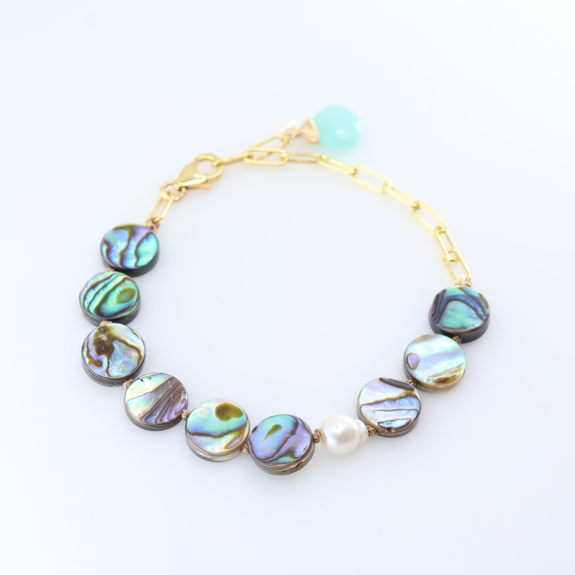 A gold chain bracelet featuring round iridescent abalone shell with shimmering green, blue, and purple hues, accented by a single white pearl bead and a Dark Aqua Chalcedony accent.